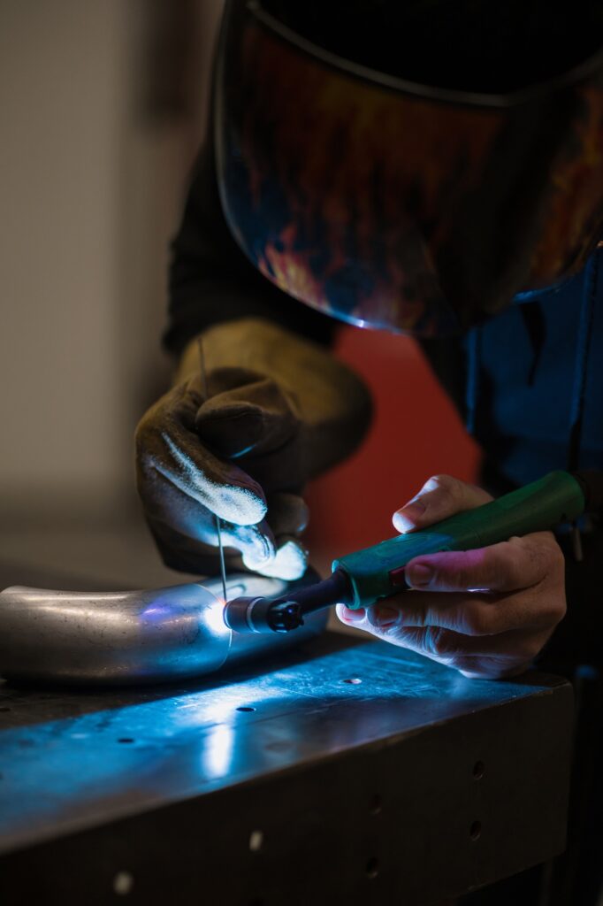 Man using welding machine in His garage. He is repairing a metal motorcycle part. Jobs and hobbies